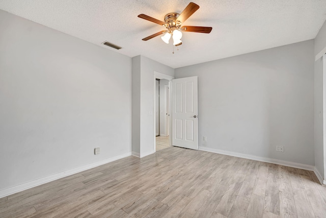 spare room with visible vents, light wood-style flooring, a ceiling fan, a textured ceiling, and baseboards