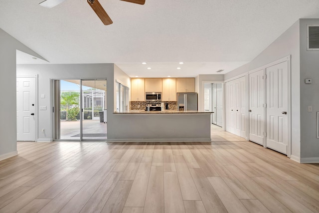 kitchen with light wood finished floors, baseboards, stainless steel appliances, and decorative backsplash