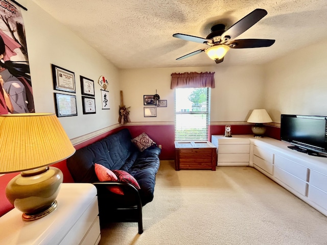 living area featuring a ceiling fan, carpet flooring, and a textured ceiling