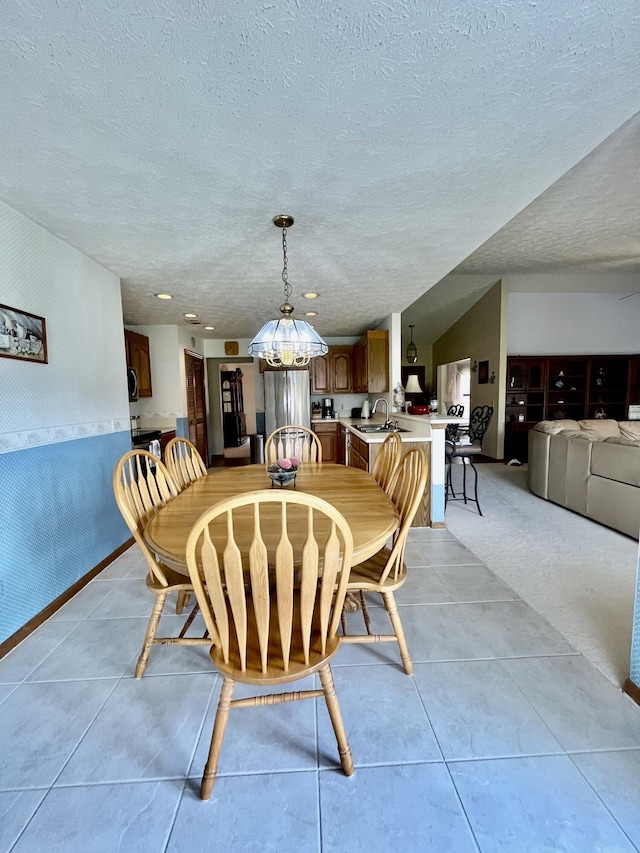 dining space featuring light tile patterned floors, baseboards, and a textured ceiling