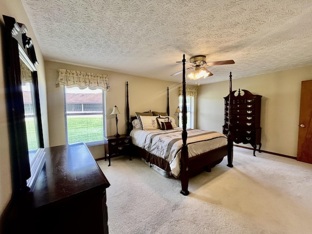 bedroom featuring light colored carpet, ceiling fan, a textured ceiling, and baseboards