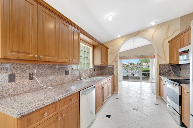 kitchen featuring stainless steel appliances, arched walkways, plenty of natural light, and a sink