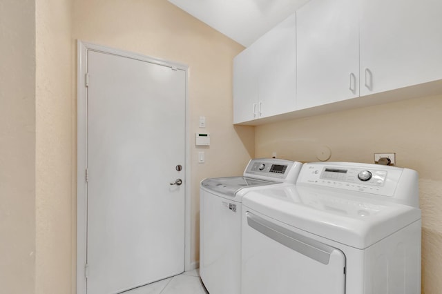 clothes washing area with cabinet space, light tile patterned floors, and washer and clothes dryer