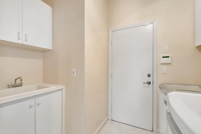 laundry room with light tile patterned floors, a sink, baseboards, washer and dryer, and cabinet space