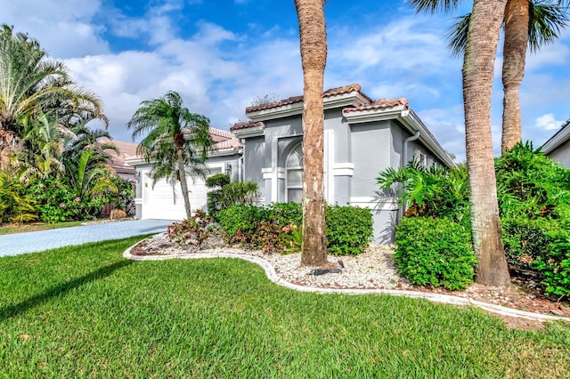 mediterranean / spanish-style house featuring a garage, a front yard, driveway, and a tiled roof