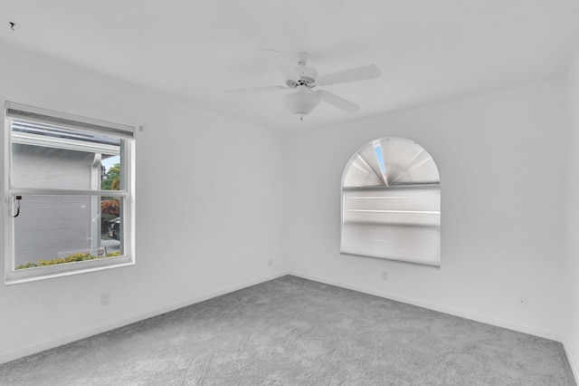 carpeted empty room featuring ceiling fan and baseboards