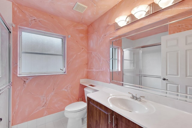 bathroom with toilet, vanity, visible vents, tile patterned floors, and a shower with door