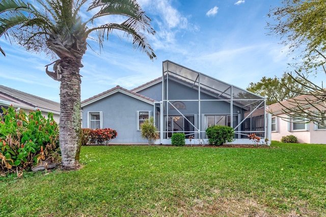 back of property featuring glass enclosure, a tiled roof, a lawn, and stucco siding