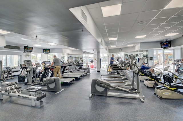 exercise room featuring a paneled ceiling, visible vents, and a healthy amount of sunlight