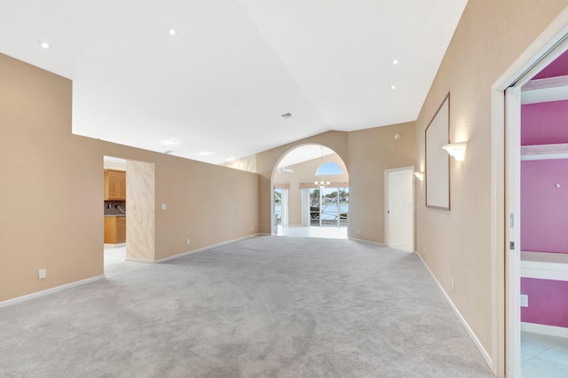 empty room featuring baseboards, high vaulted ceiling, and light colored carpet