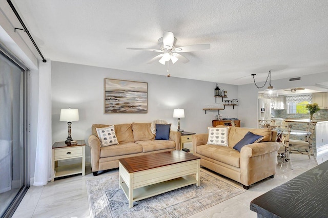 living room featuring ceiling fan, marble finish floor, and visible vents