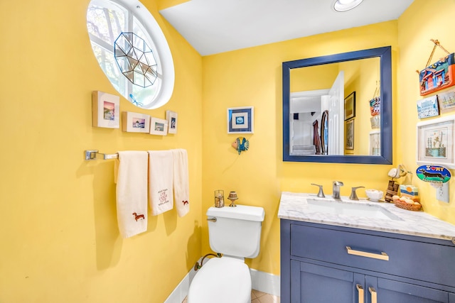 bathroom with baseboards, vanity, and toilet