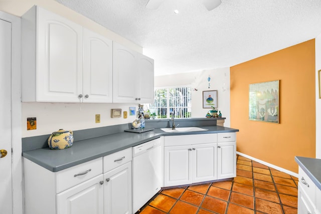 kitchen with dark countertops, white cabinets, white dishwasher, and a sink