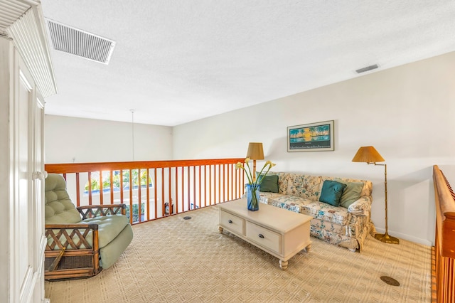 sitting room featuring light carpet, a textured ceiling, visible vents, and baseboards