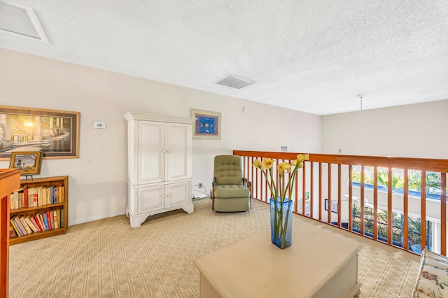 living area with light carpet, baseboards, visible vents, and a textured ceiling