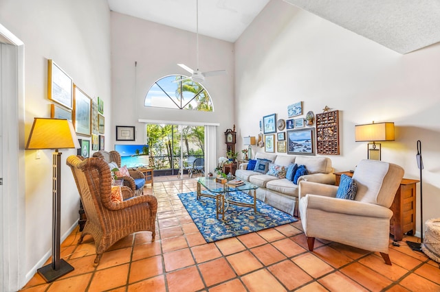 tiled living room with a ceiling fan, a towering ceiling, and baseboards