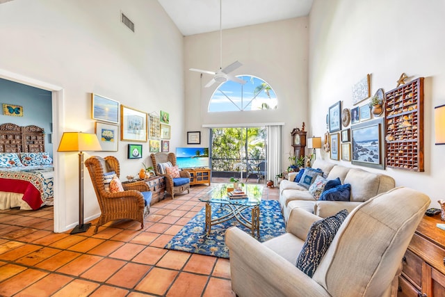 living area with light tile patterned floors, ceiling fan, a high ceiling, and visible vents