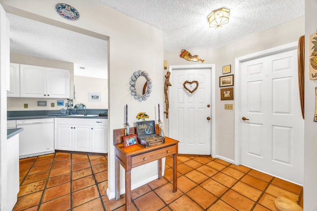 foyer entrance featuring light tile patterned floors, a textured ceiling, and baseboards