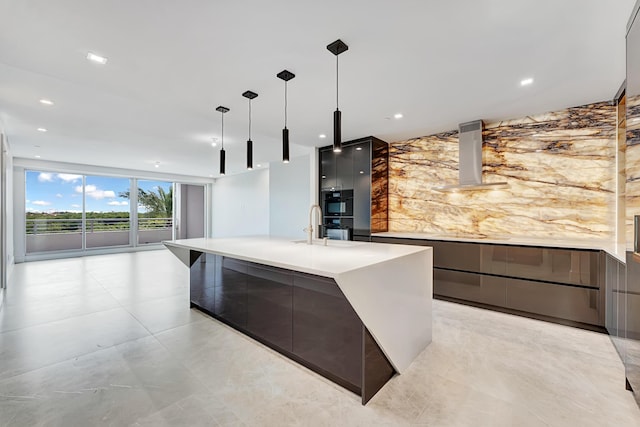 kitchen featuring modern cabinets, hanging light fixtures, range hood, a wall of windows, and light countertops