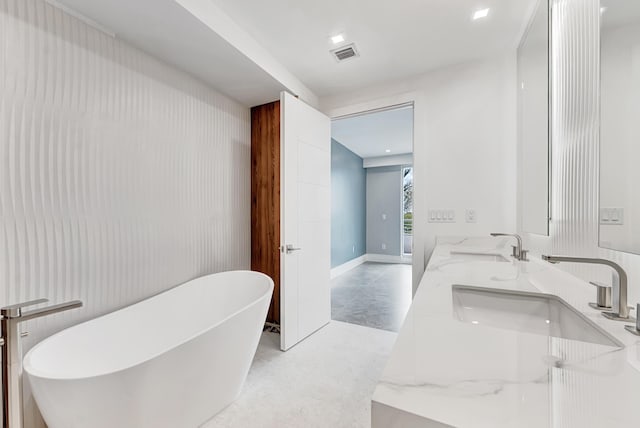 bathroom featuring double vanity, a freestanding tub, a sink, and visible vents