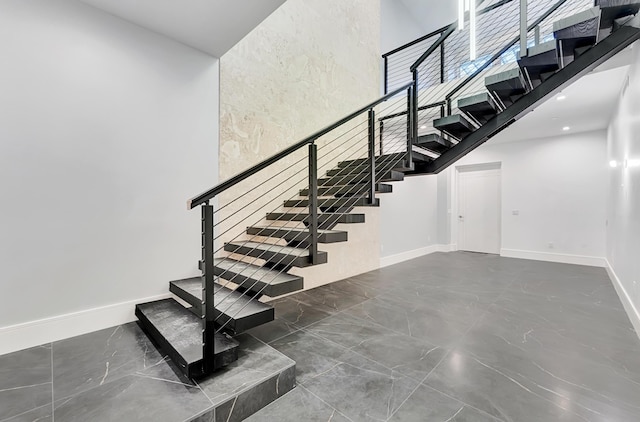 stairway with a high ceiling and baseboards