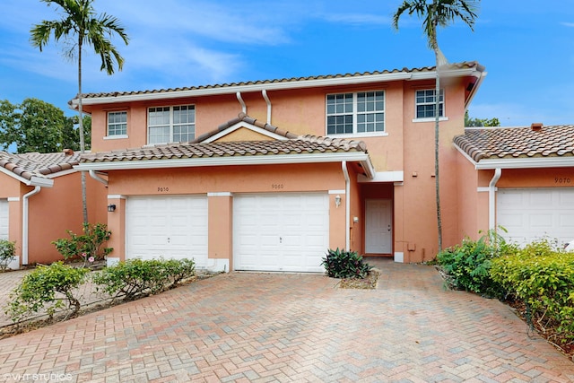 view of front of house featuring a garage, a tiled roof, decorative driveway, and stucco siding