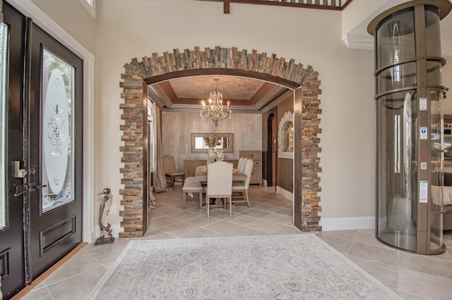 entryway with baseboards, ornamental molding, an inviting chandelier, tile patterned flooring, and arched walkways