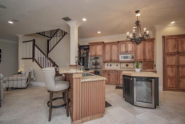 kitchen featuring visible vents, brown cabinets, wine cooler, double oven, and a sink