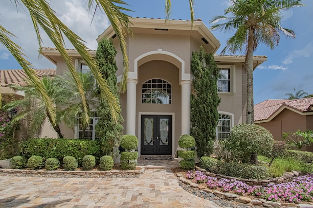 entrance to property with french doors, a tile roof, and stucco siding