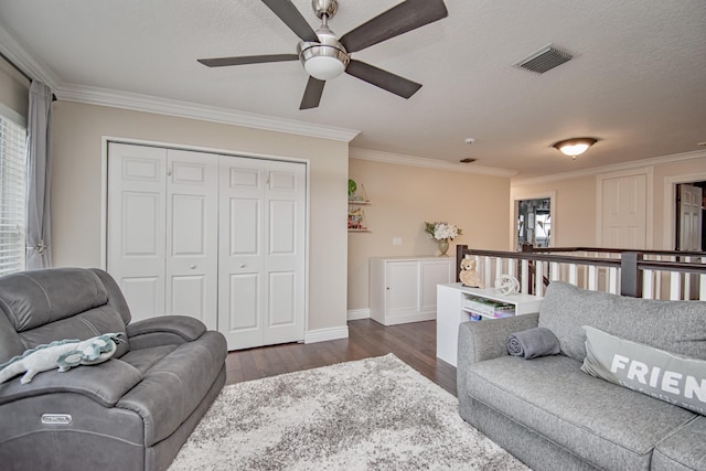 living room with dark wood-type flooring, visible vents, a ceiling fan, and crown molding