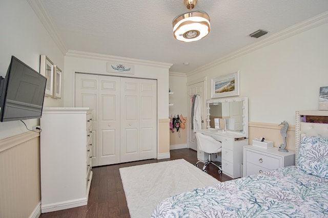 bedroom featuring a textured ceiling, a closet, ornamental molding, visible vents, and dark wood-style flooring