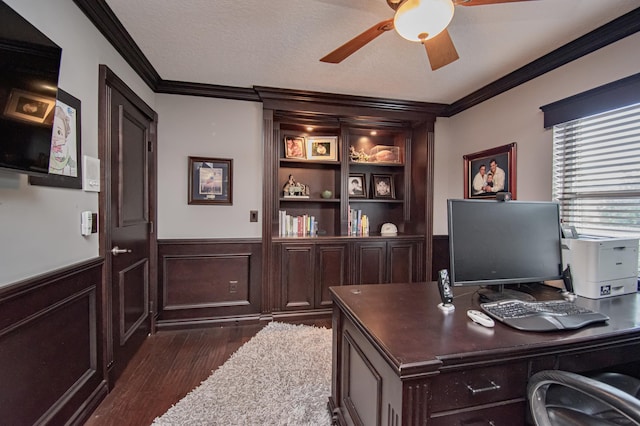 home office with dark wood-type flooring, ornamental molding, a wainscoted wall, and ceiling fan