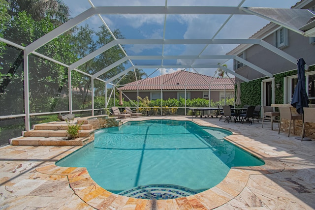 outdoor pool featuring a patio area, an in ground hot tub, and glass enclosure