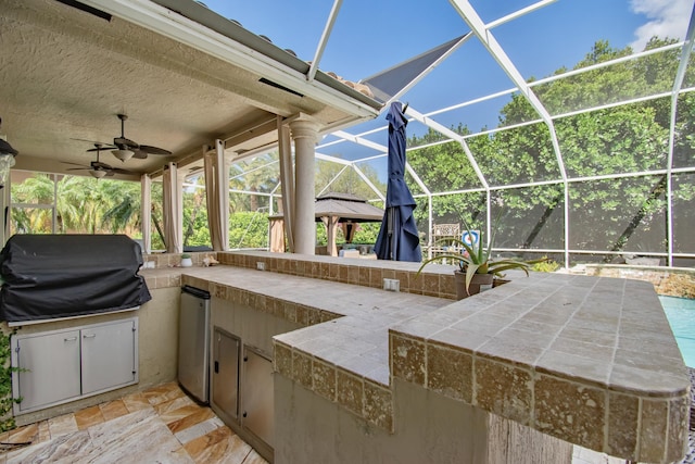 view of patio / terrace with area for grilling, an outdoor kitchen, a ceiling fan, and a lanai