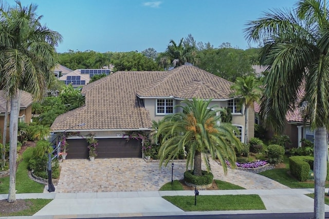 view of front of home with a garage, stucco siding, a tile roof, and decorative driveway
