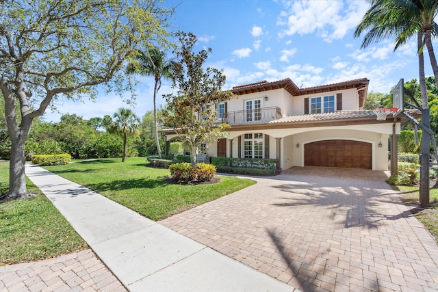 mediterranean / spanish-style house with stucco siding, a front yard, a balcony, a garage, and a tiled roof