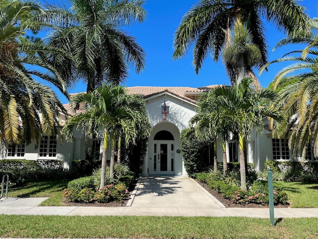 mediterranean / spanish-style home with a tiled roof, french doors, and stucco siding