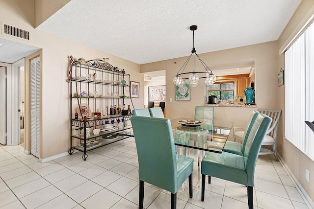 dining space featuring light tile patterned flooring, visible vents, a textured ceiling, and baseboards