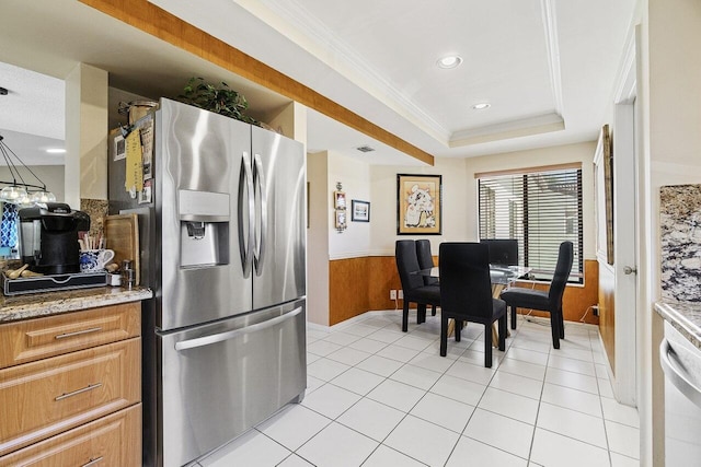 kitchen with a wainscoted wall, ornamental molding, a tray ceiling, stainless steel fridge, and wood walls