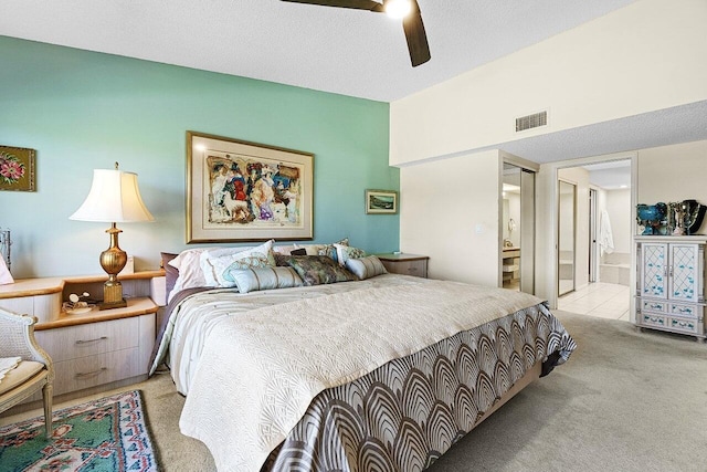 carpeted bedroom featuring visible vents, lofted ceiling, ensuite bathroom, a textured ceiling, and a ceiling fan