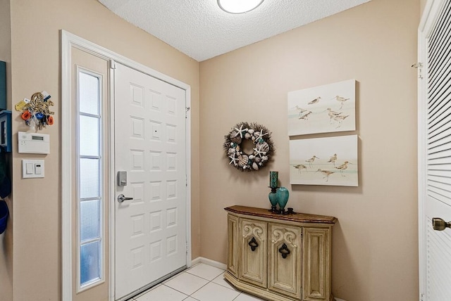 entrance foyer with light tile patterned floors, baseboards, and a textured ceiling