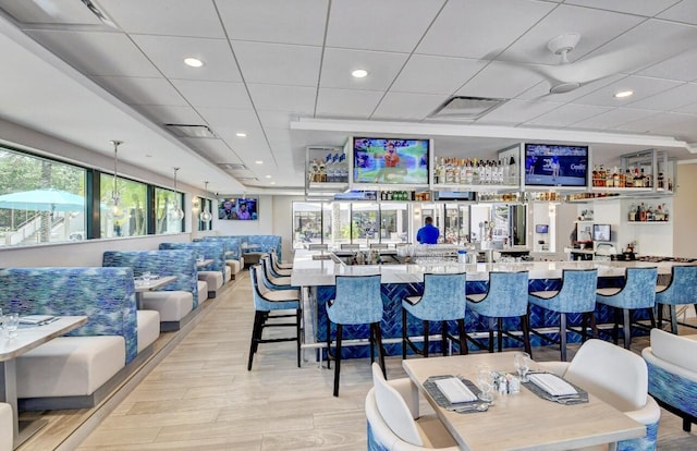 bar with indoor wet bar, recessed lighting, a healthy amount of sunlight, and light wood-type flooring