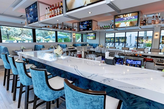 bar with indoor wet bar and wood finished floors