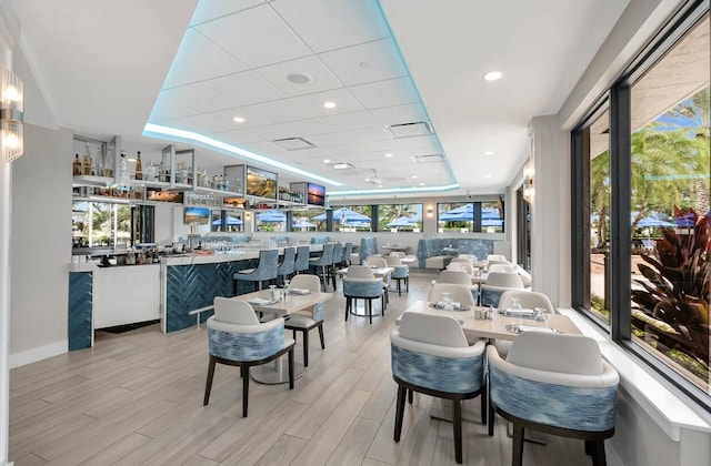 dining space with plenty of natural light, light wood-type flooring, and a tray ceiling