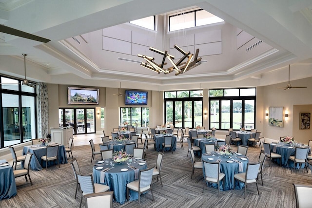 dining space with ceiling fan with notable chandelier, crown molding, a tray ceiling, and a towering ceiling