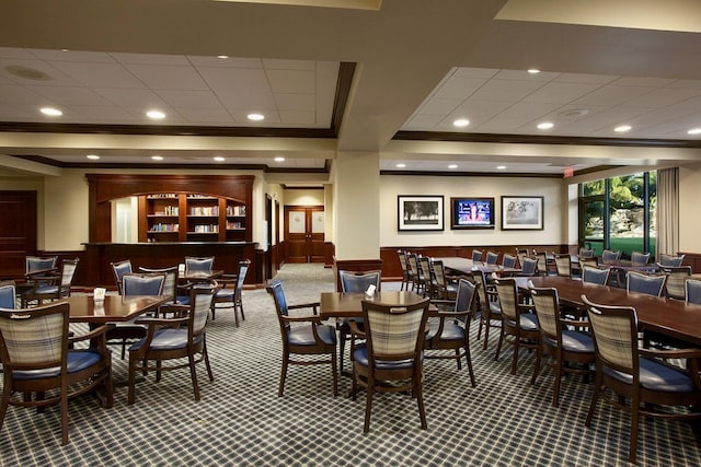 carpeted dining space featuring crown molding, recessed lighting, and a wainscoted wall