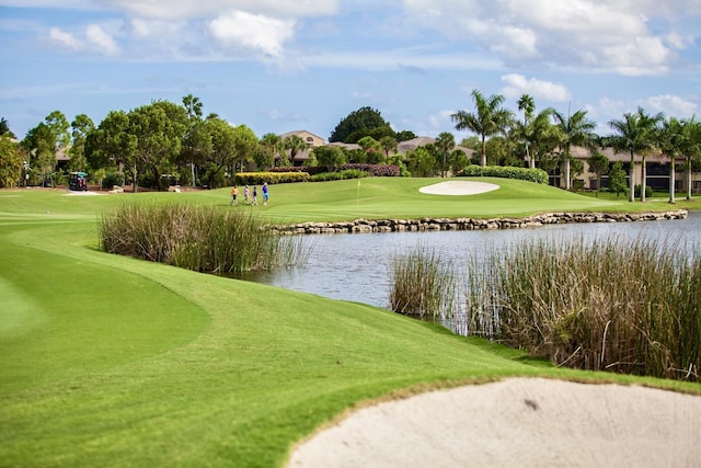 view of property's community featuring a yard, a water view, and view of golf course