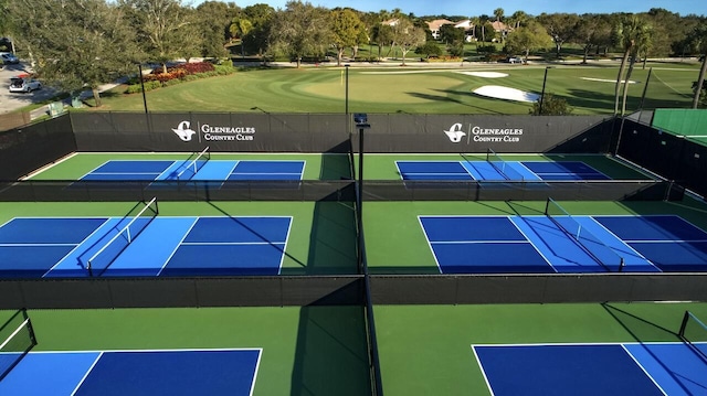 view of tennis court with view of golf course and fence