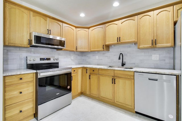 kitchen featuring stainless steel appliances, recessed lighting, tasteful backsplash, light brown cabinets, and a sink