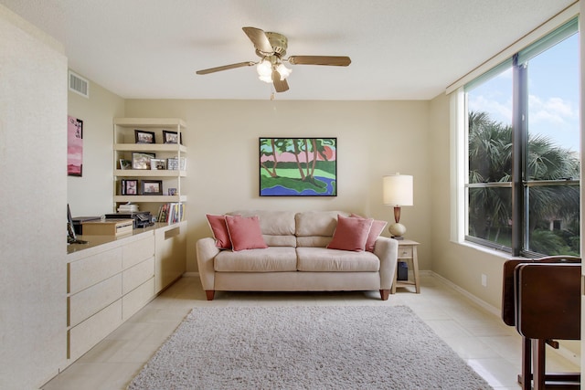 living area with baseboards, visible vents, and a ceiling fan